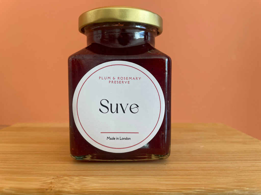 One square jar of plum and rosemary preserve on wooden surface 